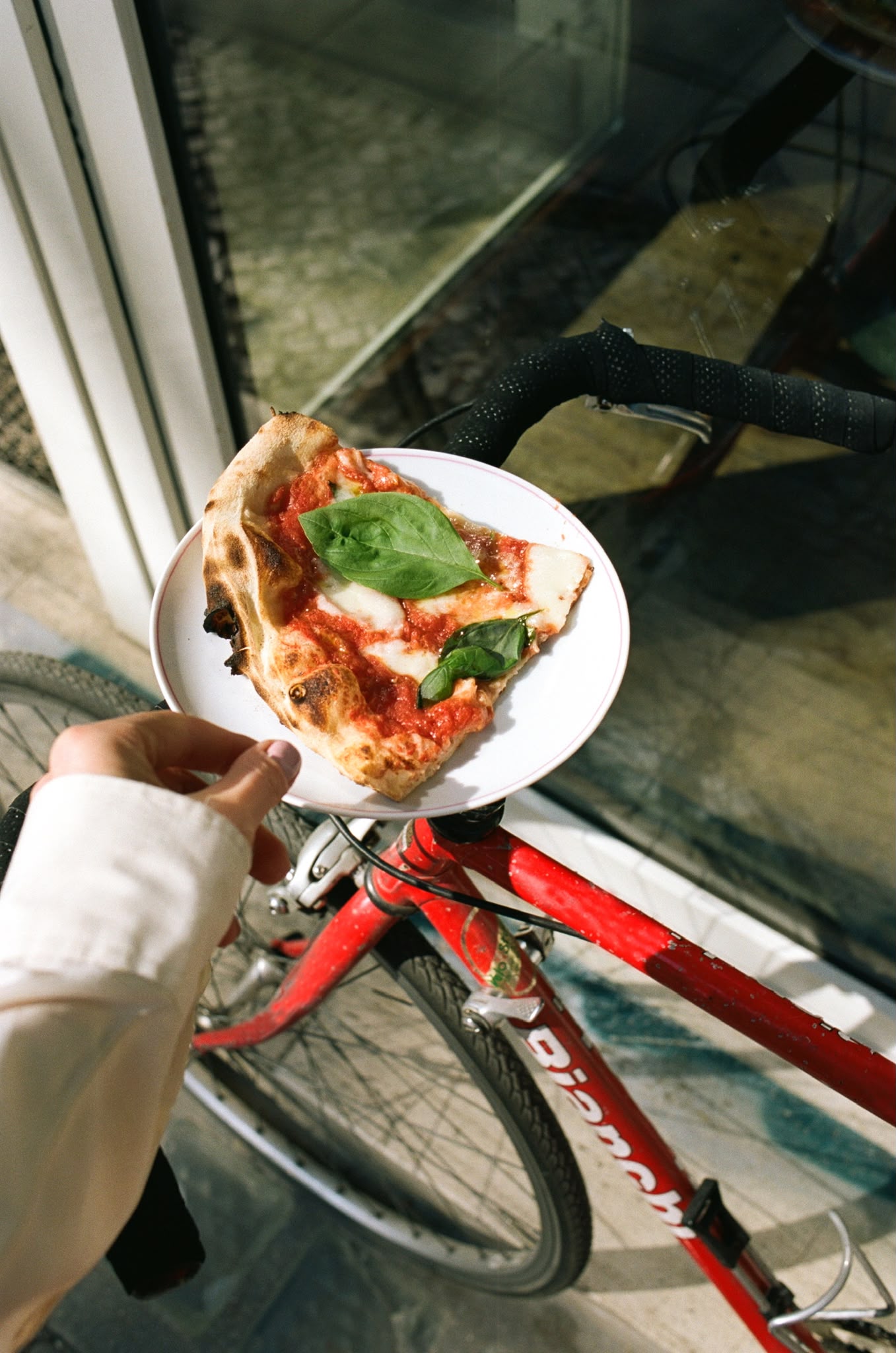 A slice of Margherita balanced on a red Bianchi bike